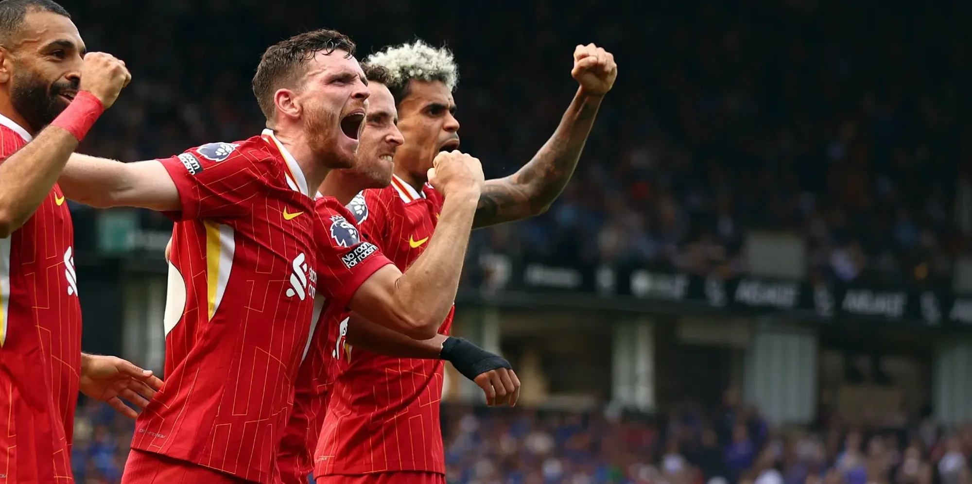 Liverpool players celebrating during their Premier League match against Ipswich Town in the 2024-2025 season, with players in red kits raising their fists in celebration